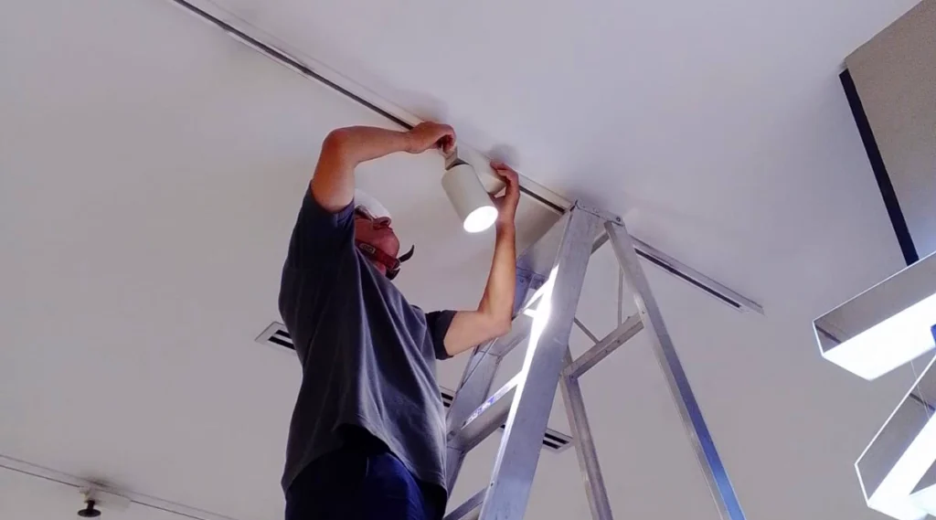 Técnico de Soluciones Azur realizando reparación de luminarias en el techo de un local comercial en Medellín