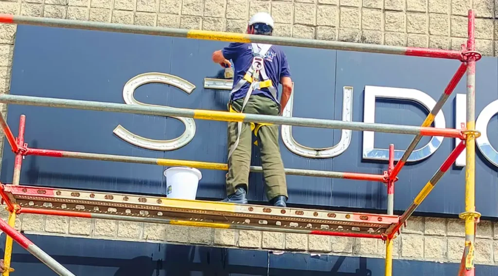 Técnico de Soluciones Azur realizando mantenimiento de aviso luminoso en fachada de local comercial en Medellín